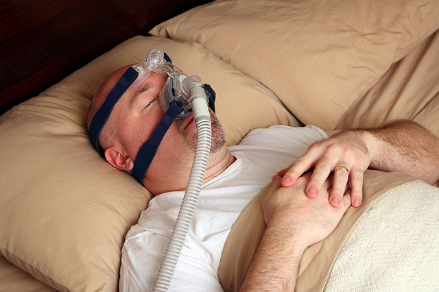 man in bed wearing full face cpap mask