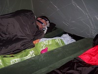 man in sleeping bag wearing CPAP