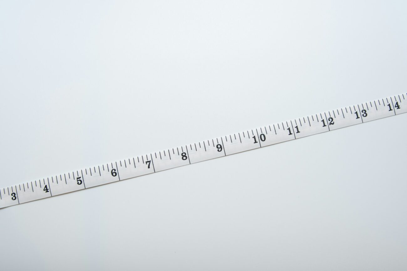 A white measuring tape stretched diagonally across a plain white surface